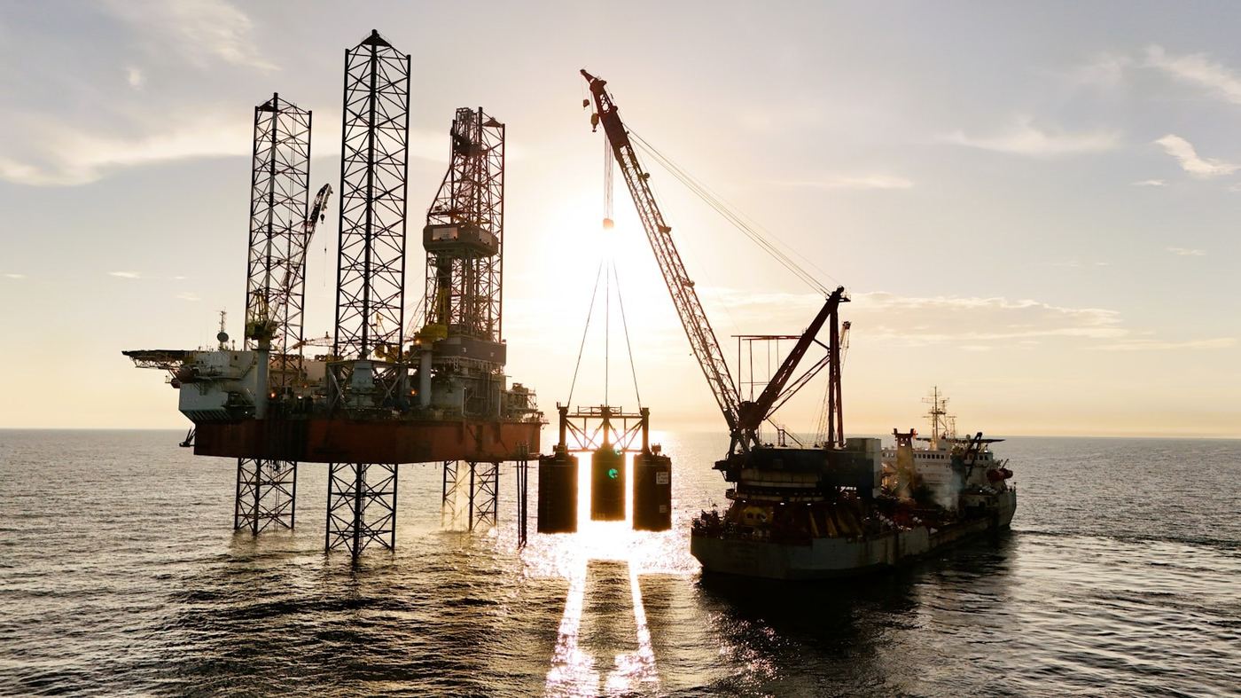 Jack up rig and a crane vessel at sea at sunset