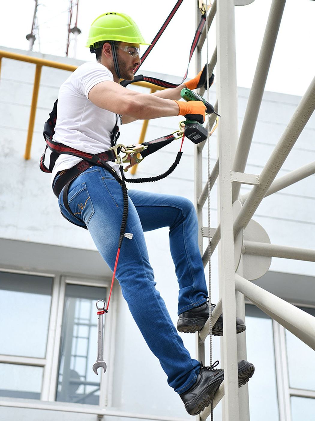 Worker in a full body harness clipping a lanyard while climbing a steel structure